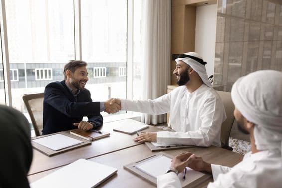 Többnemzetiségű üzleti partnerek, akik kézfogással fejezik be a sikeres tárgyalást.