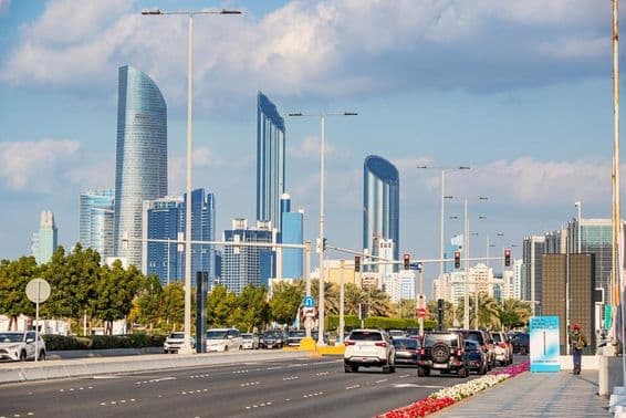 Abu Dhabi, modern felhőkarcolók tornyosulnak háttérben a forgalmas Corniche út mögött.