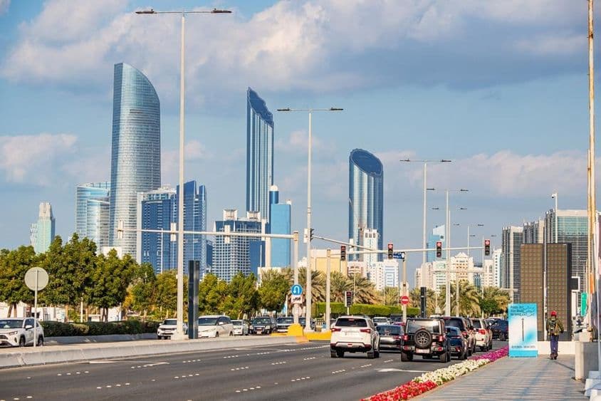 Abu Dhabi, modern felhőkarcolók tornyosulnak háttérben a forgalmas Corniche út mögött.