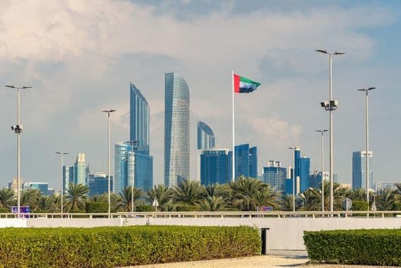 Abu Dhabi ikonikus látképe modern felhőkarcolóval és jól látható nemzeti zászlóval.