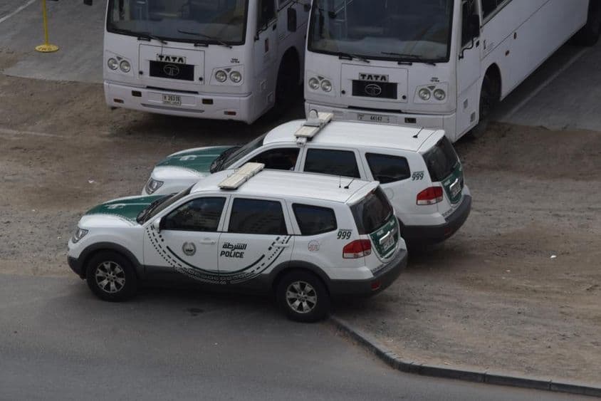 Két dubaji rendőrautó parkolt két busz előtt a dubaji AL qouzban.