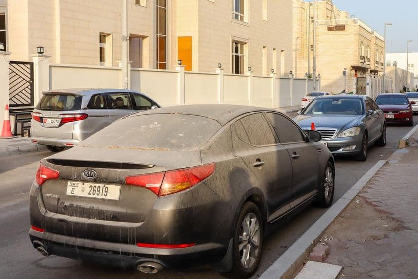 Poros és homokos dubai rendszámú autók parkolása abu dhabi-ban.