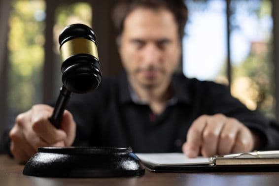 Bíró kalapácsot tart a kezében, hogy jelt adjon a tárgyalás befejezése után.