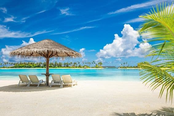 Maldív-szigeteki homokos tengerpart, napernyővel, nyugággyal.