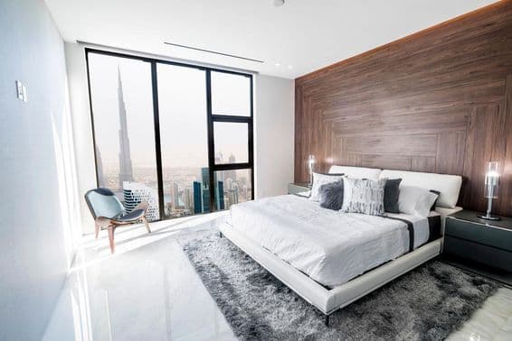 Luxus hálószoba fehér mennyezettel és fa díszítéssel, kilátással Dubai belvárosára.