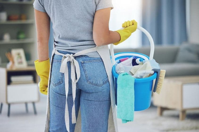 Háztartási alkalmazott dolgozik egy nappaliban.