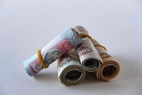 UAE dirham valuta és érmék gyűjteménye feltekerve és egymásra rakva.