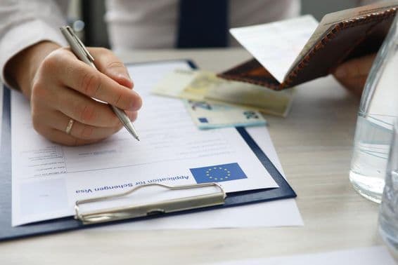 Férfi kezében az útlevél és a személyes adatok beírása a schengeni vízumkérelmen.