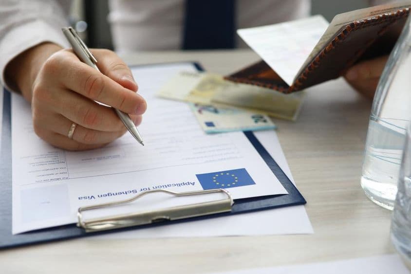 Férfi kezében az útlevél és a személyes adatok beírása a schengeni vízumkérelmen.