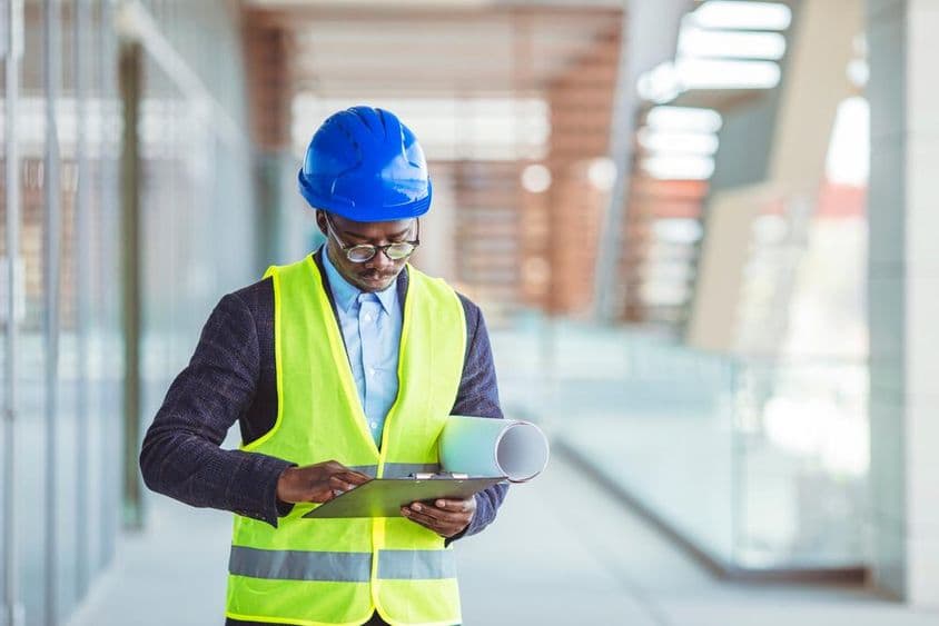 Fiatal építőmérnök papíralapú statisztikákat elemez.