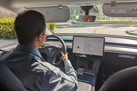 Dubai sofőr egy Tesla autót vezet egy városi úton.