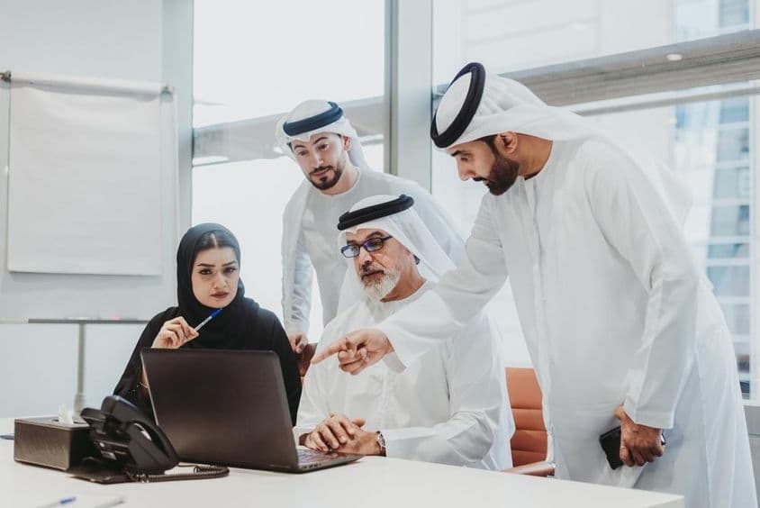 Emirátusi ruhát viselő üzletemberek csoportja találkozón az irodában Dubaiban.
