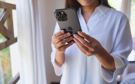 Egy nő otthon használja az iPhone 15 Pro Max.