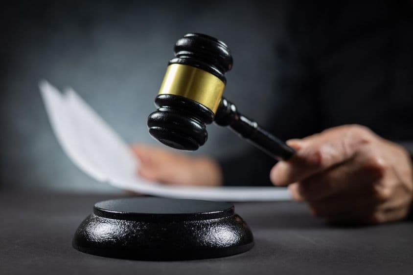 Bíró papírlappal hirdet ítéletet a bíróságon.