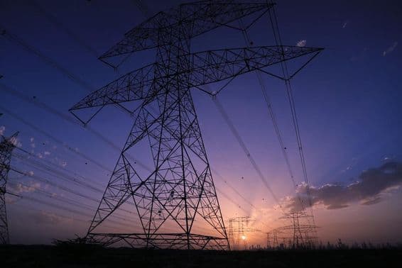 Nagyfeszültségű tornyok naplemente alatt Dubai városának látképével.