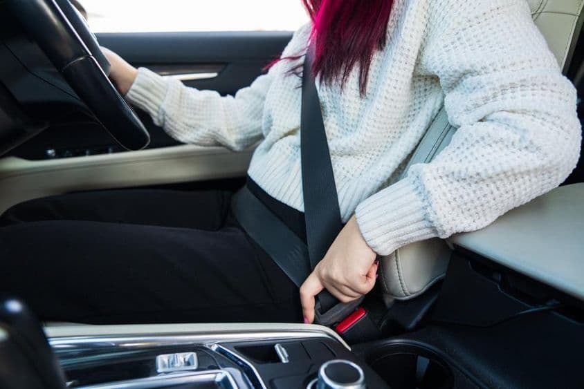 Női sofőr beköti a biztonsági övet.