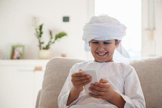 Arab fiú okostelefont használ otthon.