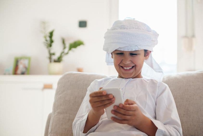 Arab fiú okostelefont használ otthon.