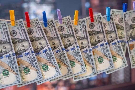 100 új dolláros bankjegy lóg a ruhaszárító kötélen fakapcsokkal.