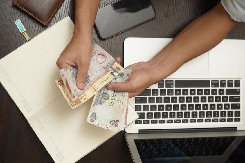 Egy férfi köteg egyesült arab emírségekbeli dirham bankjegyet számol.