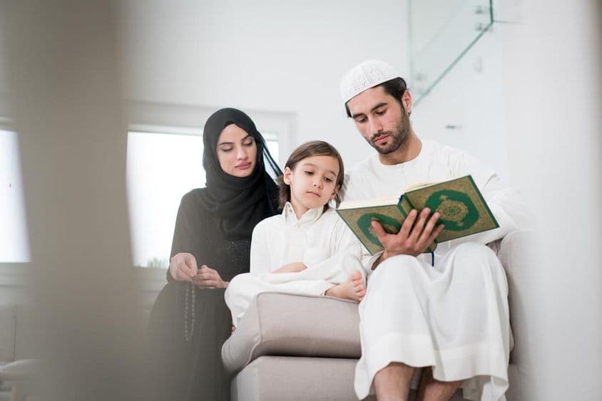 Fiatal szülők és kisfiú olvas egy könyvből.