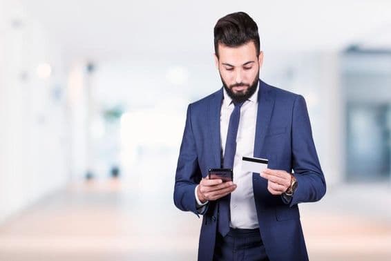 Arab üzletember, aki okostelefont és hitelkártyát tart a kezében.