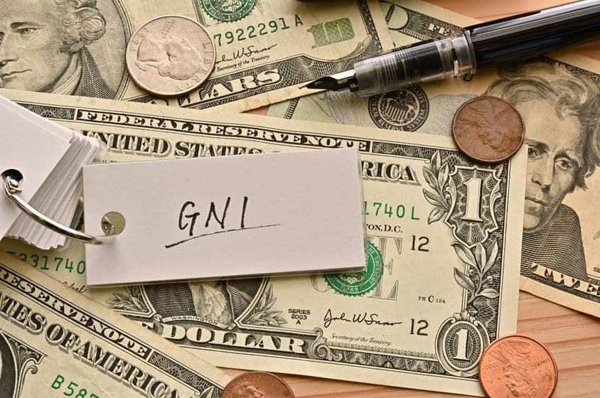 Az asztalon lévő dollárbankjegyek tetején GNI pénzügyi kifejezés van írva.