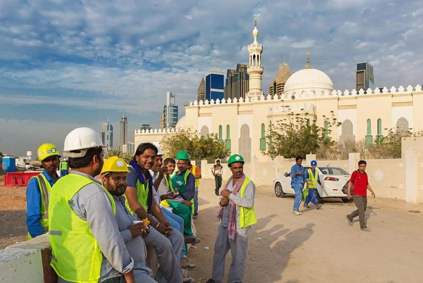 Építőmunkások szünetet tartanak egy mecset mellett a modern Dubai belvárosában.