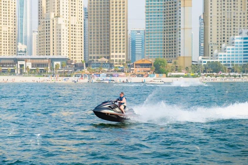 Férfi jet ski-zik a Dubai Marina Bay-ben.