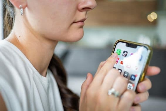 Nő iPhone-t tart a kezében képernyőn WhatsApp csevegő alkalmazással.