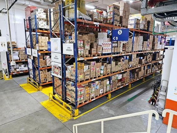 Raktár polcrendszerekkel, címkézett termékkategóriákkal és biztonsági jelölésekkel segíti a gördülékeny működést.