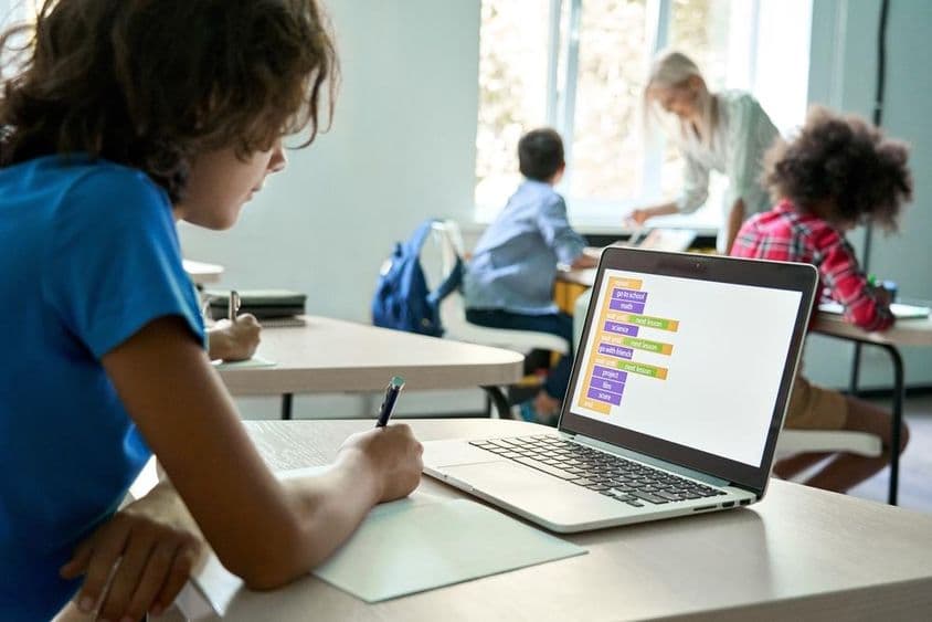 Középiskolás diák laptopot használ kódolási adatok begépelésére.