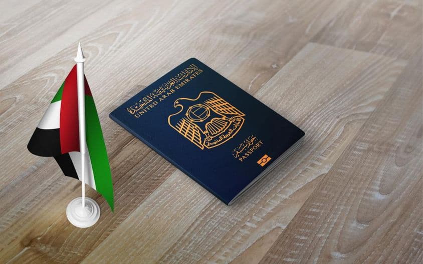 Egyesült Arab Emírségek útlevele, nemzeti zászlóval, egy fából készült háttér tetején.