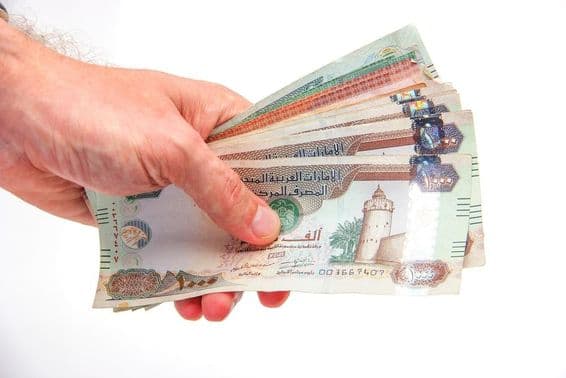 Egy férfi kezében egyesült arab emírségekbeli dirham bankjegyeket tart.