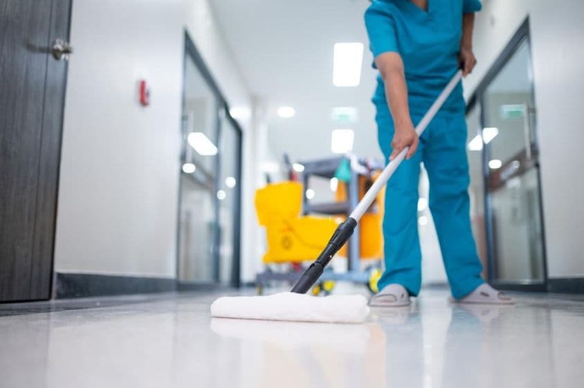 takarító felmosóval takarít a csarnok padlóján.