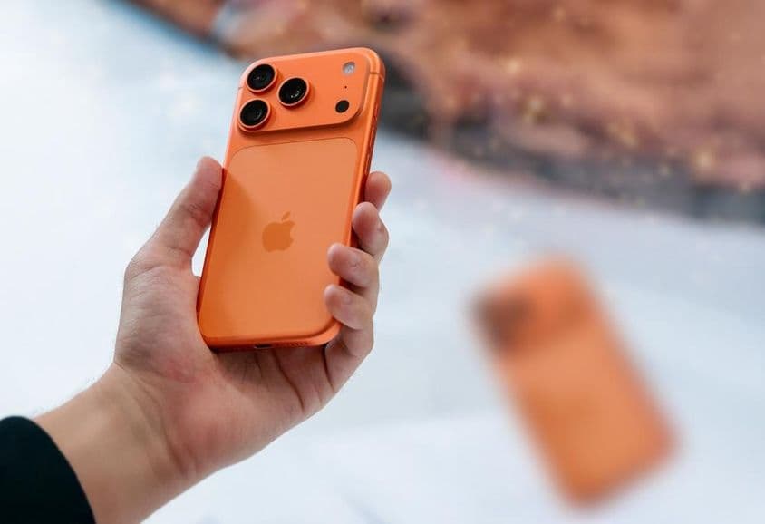 Egy férfi kezében egy narancssárga iPhone 17.