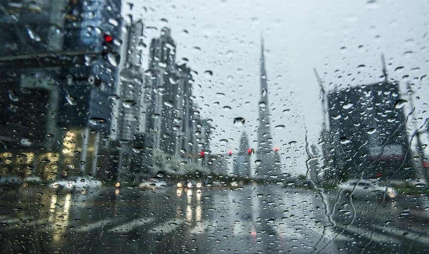 Eső Dubaiban, a városképek elmosódottnak tűnnek mögötte.