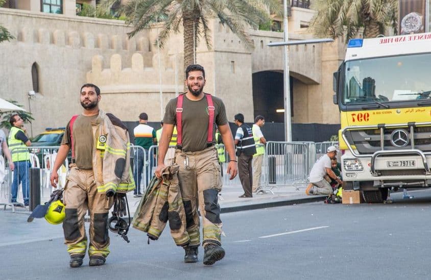 Tűzoltók sétálnak el az Address Burj Downtown Dubai épületétől.
