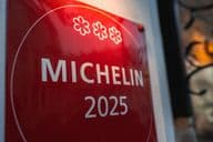 Egy piros, háromcsillagos Michelin 2025-ös emléktábla egy világos színű falon.
