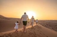 Egy család élvezi a sivatagi naplementét.