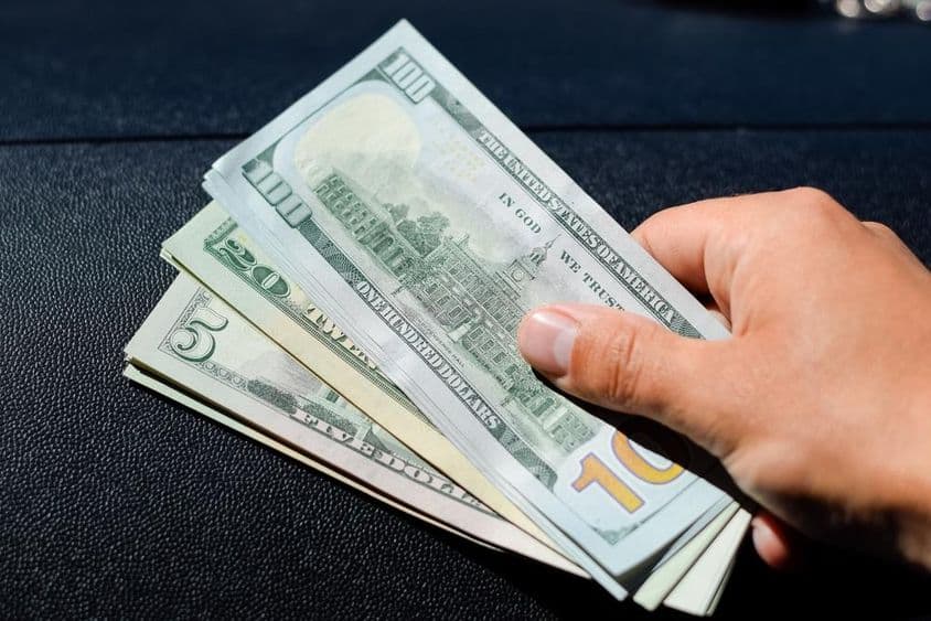 Egy köteg dollár a férfi kezében.