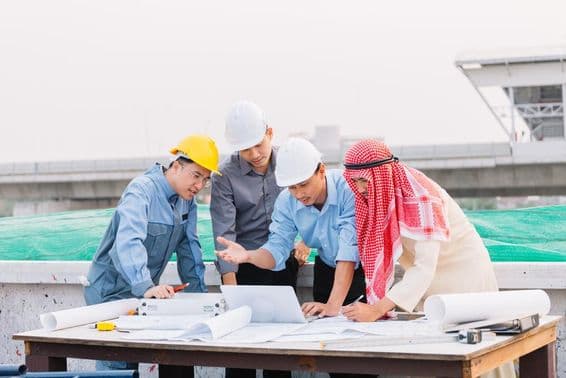 Arab üzletember, mérnök és munkás dolgozik és beszélget laptoppal az építési terveken.