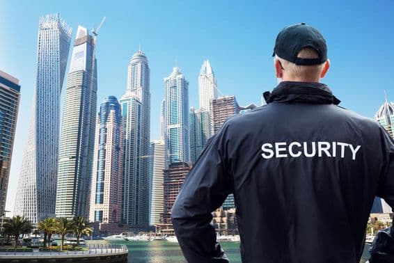 Férfi biztonsági őr hátulról nézi a város látképét.