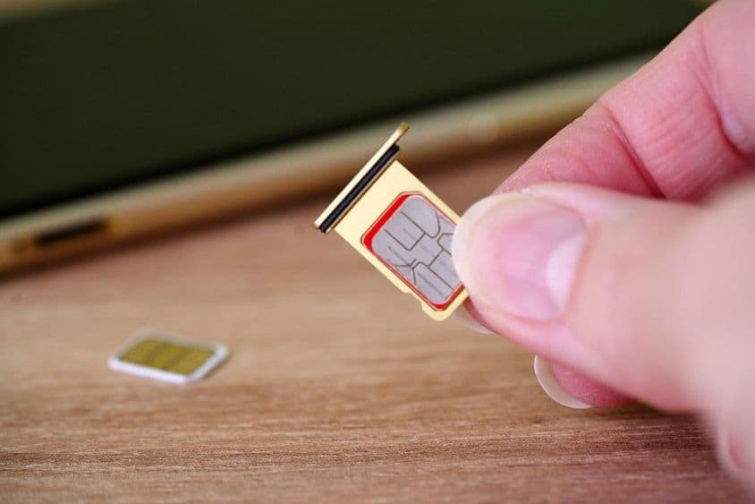 Sim kártyát behelyező személy a mobiltelefon hátuljába.