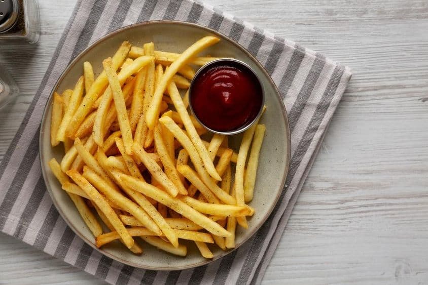 Házi készítésű sült krumpli és ketchup egy tányéron.
