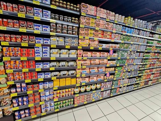 szupermarket polc színes konzervekkel, tonhallal és zöldségekkel