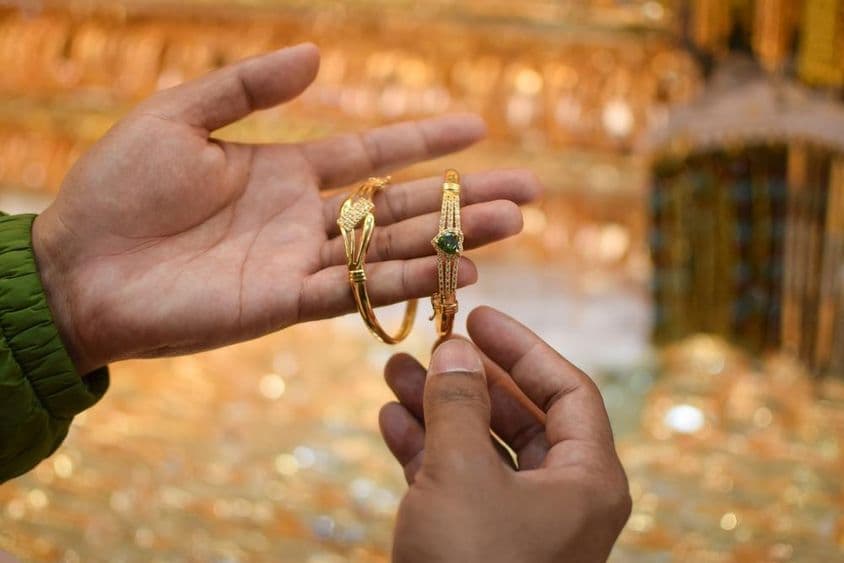 Egy kéz felpróbál egy luxus arany karkötőt egy ékszerüzletben