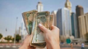 az Egyesült Arab Emírségek pénze a dubai felhőkarcolók hátterében.