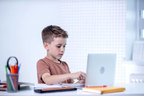 Iskolás gyerek számítógéppel videokonferencián beszélget a tanárral