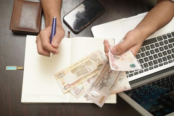 férfi egy köteg egyesült arab emírségekbeli dirham bankjegyet számol.